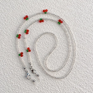 Detail of beaded glasses chain with red cherries, green leaves and silver metal lobster clasps