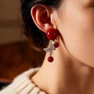 Détail d'une boucle d'oreille papillon rouge plaquée or 18 carats sur le mannequin