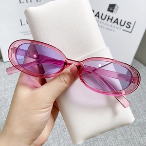 Close-up of translucent purple cat eye sunglasses held by hand over a white case