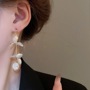 Detail of floral tassel earrings with pearl petals and gold chain on model