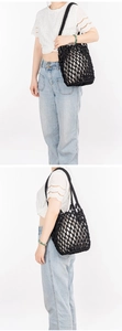 Detail of a handmade black cotton rope mesh shoulder bag worn on the shoulder