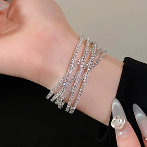 Detailopname van een meerlaagse zilveren wikkelarmband met fonkelende strasstenen
