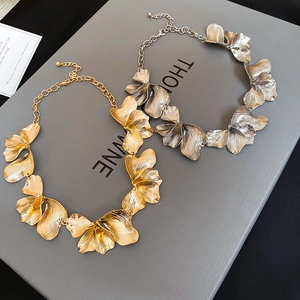 Detailed macro view of gold and silver textured flower necklaces with brushed metal finish