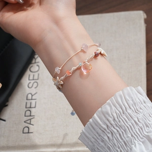 Detail of handmade seashell and starfish woven bracelets with heart charms on wrist