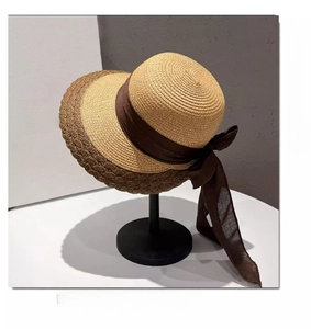 Detail of elegant coffee brown satin bow and two-tone straw weave on sun hat brim