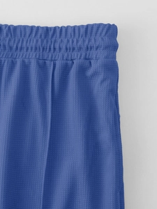 Detail of blue waffle knit joggers showing elastic waistband and breathable texture