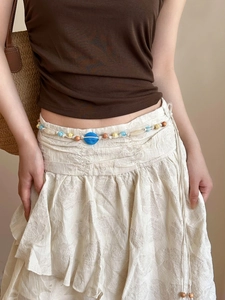 Détail d'une chaîne de taille tissée main avec perles en bois et ornement en résine bleue