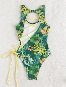 Close-up of tropical floral print swimsuit with side cut-out and yellow lacing detail