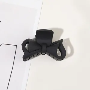 Macro detail of the matte black bow hair claw clip showing textured surface and sturdy teeth