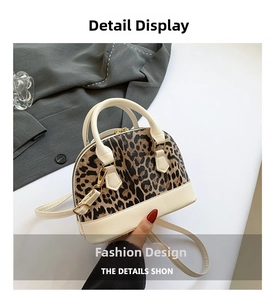 Detail of leopard print stitching and gold zipper on cream-colored shell handbag