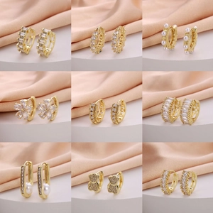 Collection of nine gold plated hoop earrings with CZ stones and pearls on silk fabric