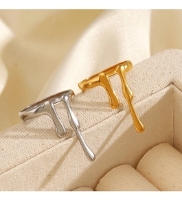 Detail view of gold and silver irregular lava drip rings on a beige fabric jewelry box