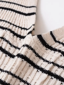 Detailed close-up of cream and black striped knit dress fabric with thick texture