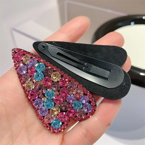 Macro view of heart-shaped hair clips with colorful rhinestones and black BB metal clasp