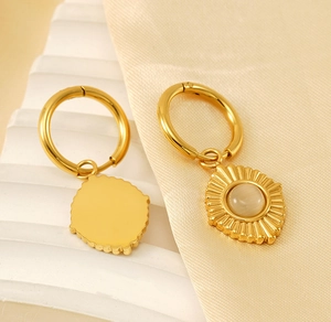 Gros plan de boucles d'oreilles soleil dorées et œil de chat sur soie douce