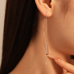 Detail of rose gold teardrop tassel earrings showing delicate chain and sleek metal curve