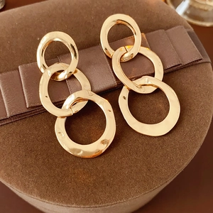 Close-up of golden interlocking triple hoop earrings on a brown ribbon jewelry box