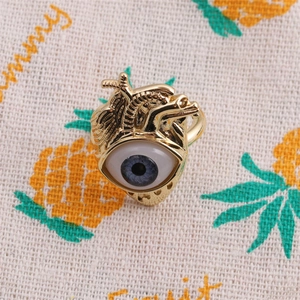 Detailed top view of gold heart ring with blue eye zircon inlay on patterned fabric