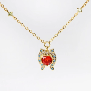 Golden necklace with a large red heart gemstone pendant and blue diamond accents