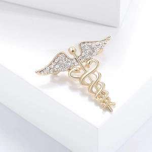 Vintage gold snake brooch with angel wings and rhinestones on a white pedestal