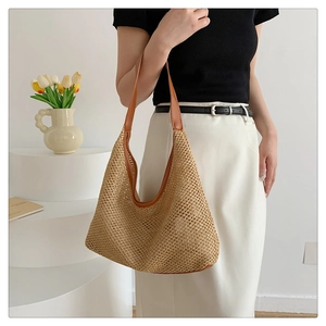 Detail of hand-woven straw tote bag with brown leather handles and natural texture