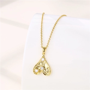 Detailed view of a gold heart pendant necklace with three zircon stones on a white stand