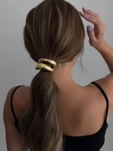 Detail of a sleek gold metal hair cuff styled on a low ponytail for a modern look