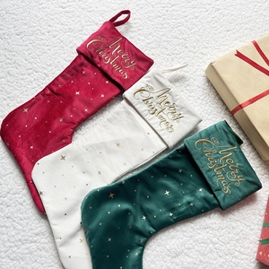 Three plush velvet Christmas stockings in red, white and green with gold star embroidery