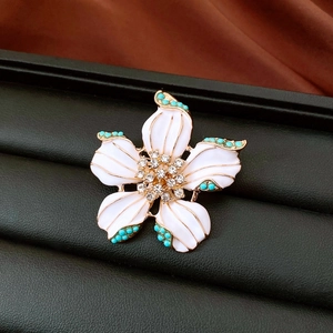 Detail view of vintage white flower brooch with turquoise beads and rhinestones in a box