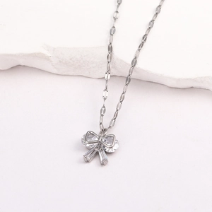 Collier à pendentif nœud en argent avec zircons clairs sur socle en marbre blanc