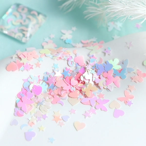 Macro view of pink iridescent butterfly and star nail sequins on white background