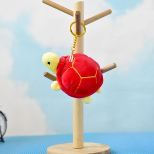Detail of a mini red plush sea turtle keychain hanging on a wooden display stand
