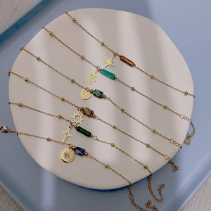 Set di bracciali boho dorati con pietre naturali e ciondoli celesti su piatto in ceramica