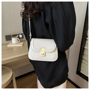 Chic off-white leather crossbody bag with a gold twist lock shown on a model