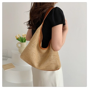 Detailed view of woven straw tote bag with brown trim on female model in a minimalist setting