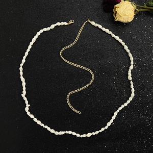 Detailed view of the layered shell shards and slim gold metal chain on a black background