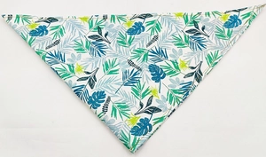 Detailed view of dog bandana with vibrant tropical green leaf patterns on white fabric