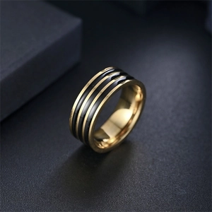 Macro di un anello largo in acciaio al titanio con bordi dorati e tre strisce di smalto