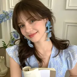 Detailed view of light blue petal tassel earrings with beads worn by a model