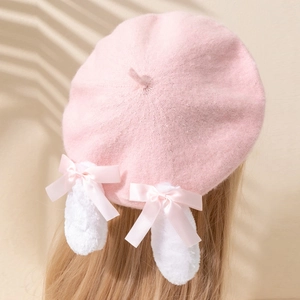 Détail du béret tricoté rose avec oreilles de lapin en peluche blanche et nœuds
