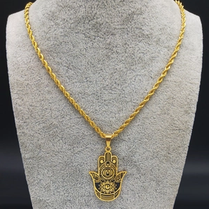Détail du pendentif main de Fatma dorée avec œil protecteur sur un présentoir à bijoux