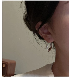 Nahaufnahme von S925 Silber Creolen mit gedrehtem Muster am Ohr im minimalistischen Stil