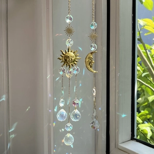 Hanging crystal suncatchers with gold sun and moon motifs casting rainbow light