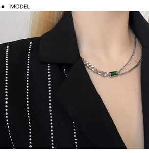Detail of layered silver chain necklace featuring a rectangular emerald gemstone pendant