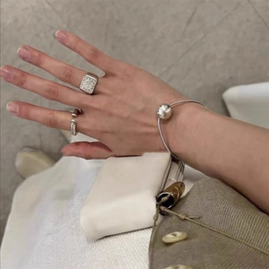 Close-up of polished silver ball elastic hair tie and metallic rings worn on hand