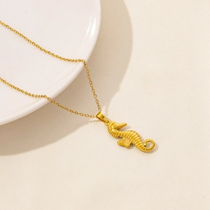 Detailed macro shot of a golden seahorse pendant necklace on a minimalist textured surface