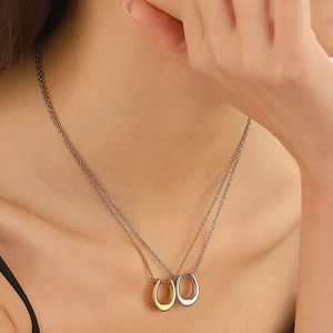 Detail of layered titanium horseshoe U-shaped necklace in gold and silver finish