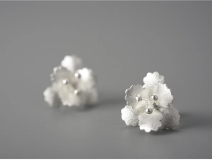 Macro shot of 925 sterling silver begonia flower earrings with matte frosted finish