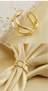 Detailed view of gold woven texture open ring displayed on silk and stone background
