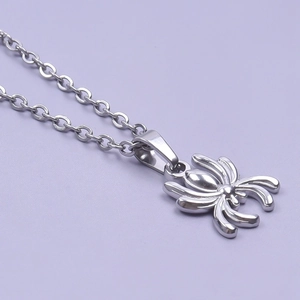 Polished silver stainless steel spider pendant necklace on a soft purple background